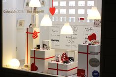 a display window with many different items in the front and behind it is a white wall that has red lettering on it