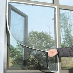 a man is opening the side of a window with his hand and holding it in front of him