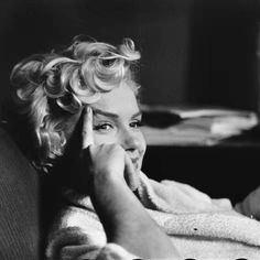 a black and white photo of a woman laying in bed with her hand on her face