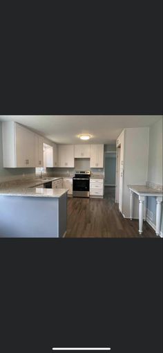 an empty kitchen with white cabinets and black appliances in the middle of it, next to a stove top oven