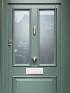 a green front door with two glass panels and a metal handle on the bottom part