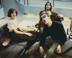 three people sitting on couches in an airport waiting area