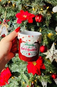 someone holding up a coffee cup in front of a christmas tree with poinsettis