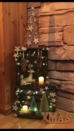 a wooden box with christmas decorations and candles on the floor in front of a stone wall