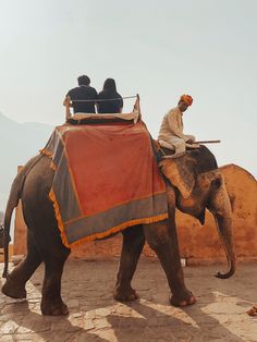 two men riding on the back of an elephant