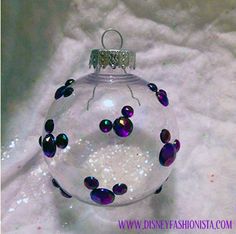 a glass ornament with purple and black beads on it sitting on a white surface