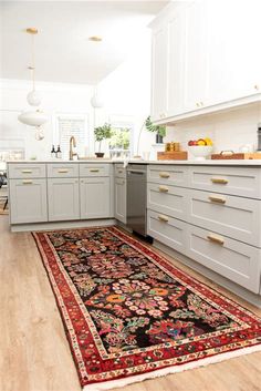 a rug in the middle of a kitchen with white cupboards and drawers on both sides