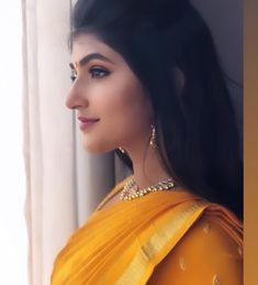 a woman with long black hair wearing a yellow sari