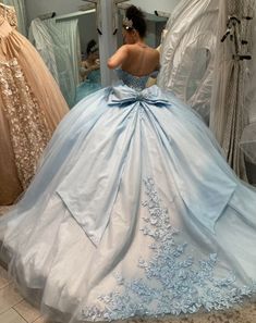 a woman in a blue ball gown looking at herself in the mirror