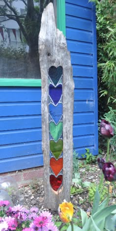 a piece of driftwood that has been made into a colorful stained glass window in front of a blue house