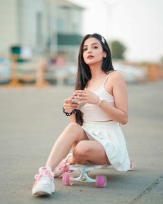 a young woman sitting on top of a skateboard