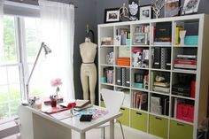 a room with a desk, bookshelf and mannequin