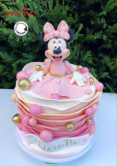 a minnie mouse cake with pink and gold decorations