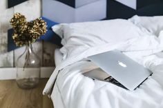 an apple laptop sitting on top of a bed in a room with blue and white walls