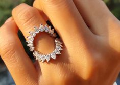 a close up of a person's hand holding a ring with diamonds on it