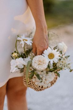 a person holding a basket with flowers in it