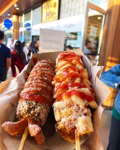 two skewers filled with meat covered in ketchup sitting on top of paper