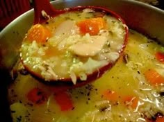 a close up of a bowl of food with broth and carrots on it