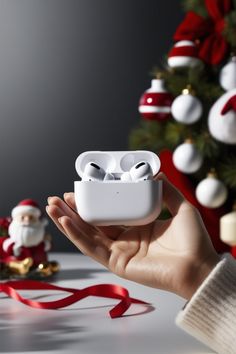 someone holding up an airpods in front of a christmas tree with ornaments on it