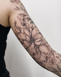 a woman's arm with flowers and leaves tattooed on the left side of her arm