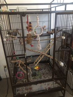 a bird cage filled with lots of birds in it's cages and some toys on the floor