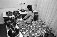 a woman sitting at a table with records on it