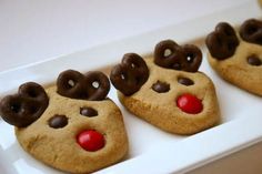 three cookies shaped like reindeer's with chocolate eyes and noses on them in a white box