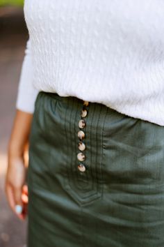 From the Flora and Henri Women's collection, the front button midi skirt in hunter green has darling tortoise buttons and detailed stitching on the waistband. Made of mid-weight cotton and easy to mix and match, this skirt is a perfect Spring capsule piece. WHY WE LOVE IT The deep hunter green acts as a neutral and offers limitless pairing opportunities for all seasons. We suggest wearing white sneakers and a lightweight cardigan in the Spring or pair it with tall boots and a chunky knit in the Green Bottoms With Buttons For Fall, Green Fall Bottoms With Buttons, Green Buttoned Workwear Bottoms, Fall Pencil Skirt With Button Closure, Green Workwear Bottoms With Buttons, Chic Green Bottoms With Buttons, Green Button-up Bottoms, Khaki Bottoms With Buttons For Fall, Khaki Midi Skirt For Fall