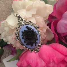 "Styled in a majestic fashion with a feminine twist, the Victorian Rose Cameo Necklace is sure to make a statement! Featuring a beautifully detailed cameo with an ebony black rose on a of Wedgwood Blue resin background. The Victorian Rose Cameo Necklace is set in a vintage-style antique silver-plated large pendant. The pendant measures approximately 2.5\" long and 2\" wide. Add on a nice antique silver-plated satellite bead chain, that closes with a lobster clasp, and may be added at checkout. C Elegant Black Jewelry With Rose Design, Resin Background, Wedgwood Blue, Cameo Jewelry, Antique Pendant, Floral Pendant, Cameo Necklace, Bead Chain, Floral Necklace