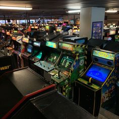 several arcade machines are lined up in an indoor gaming room with video games on the walls