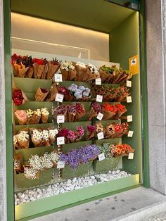 a flower shop display with lots of flowers on the outside wall and in front of it