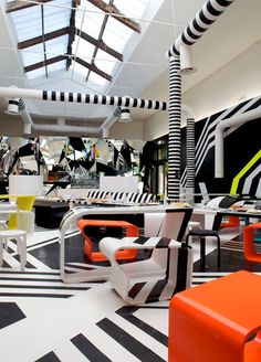 an open room with black and white flooring, orange chairs, and zebra print rugs