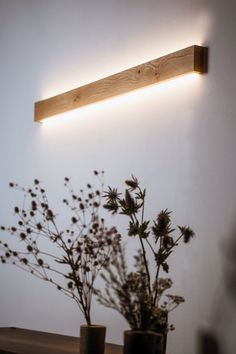 some flowers are sitting in vases on a shelf next to a light that is above them