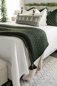 a bed with green and white pillows on it's headboard in a bedroom