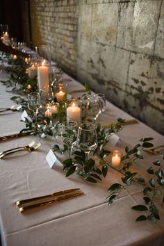 a long table with candles and greenery on it