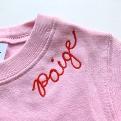 a pink shirt with the word poop embroidered on it