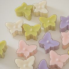 many small candles are shaped like butterflies on a white surface with one candle lit in the middle