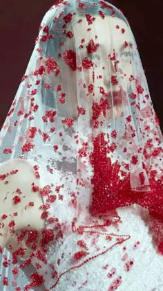 a red and white wedding gown with flowers on it's veil is seen in this image