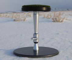 a round table with a metal base and grass on top in the middle of snow