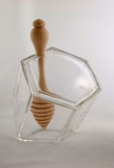 a glass container with a wooden handle on it's side and a hexagonal object in the middle