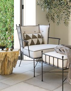 a chair and ottoman sitting next to each other on a patio with potted plants in the background