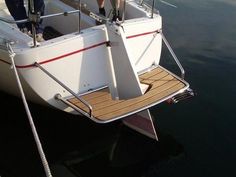 a man standing on the bow of a white boat docked at a dock with his feet in the water