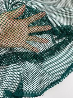 a person's hand in a green net on top of a white table cloth