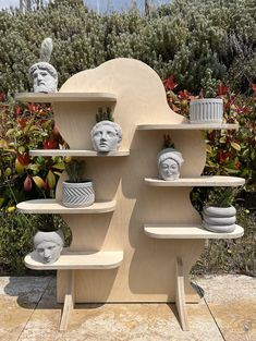 a wooden shelf filled with vases and busturines on top of each other