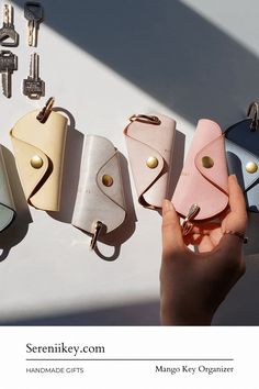 a person holding several small purses in front of key chains and keys hanging from them