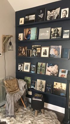 a living room filled with lots of books and pictures on the wall next to a chair