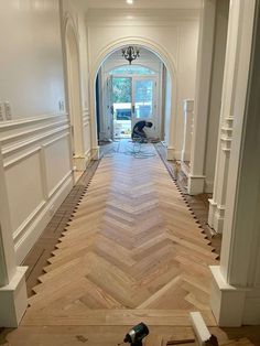 an empty hallway with hard wood floors and white trim on the walls, leading to a large doorway