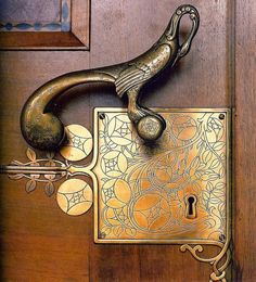 a door handle on a wooden door with an ornate design and keyhole in the middle