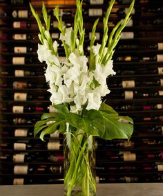 a vase filled with white flowers sitting on top of a table next to bottles of wine