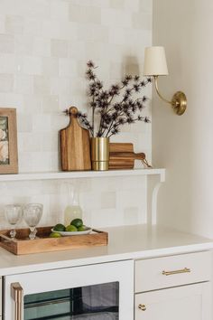 a kitchen with white cabinets and gold accents on the shelf above the oven is filled with food